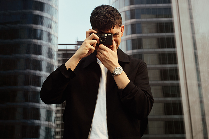 Image of a man taking a photo with a digital camera while wearing a Tissot Watch.